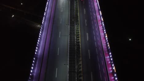 Drohnen-Topdown-Video-Einer-Brücke-Bei-Nacht,-Beleuchtet-Von-Violetten-LED-Leuchten