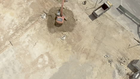 backhoe at work - scooping excavated soil at the construction site - pullback drone shot