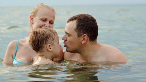 una encantadora familia con un niño bañándose en el mar