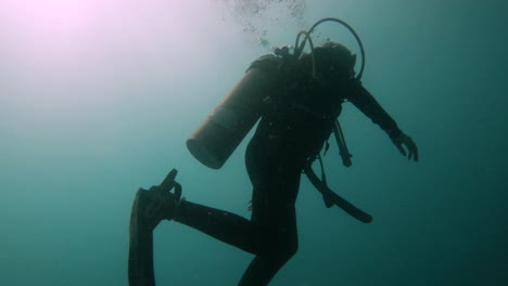 silhouette of scuba diver swimming alone in the ocean while breathing oxygen releasing bubble of air in the water 4k slow motion footage