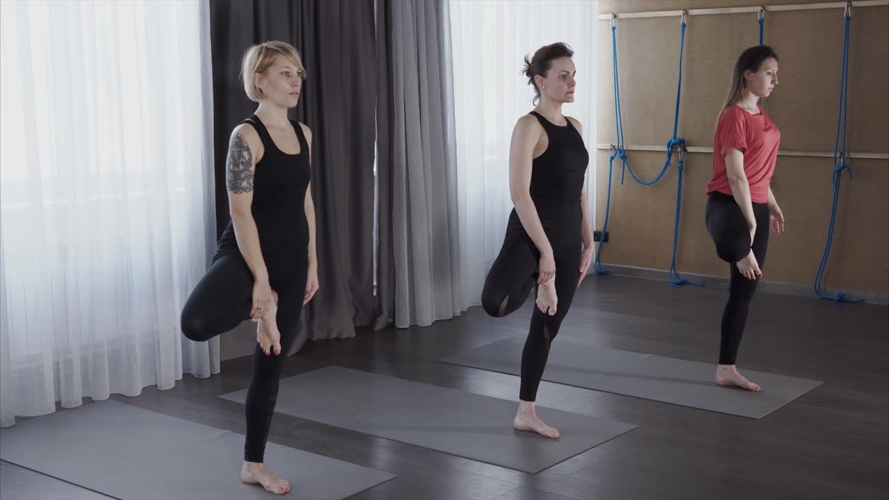 Women practicing yoga poses in a studio