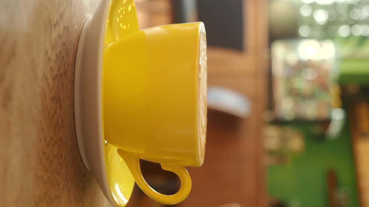 A vibrant yellow coffee cup and saucer on a wooden table
