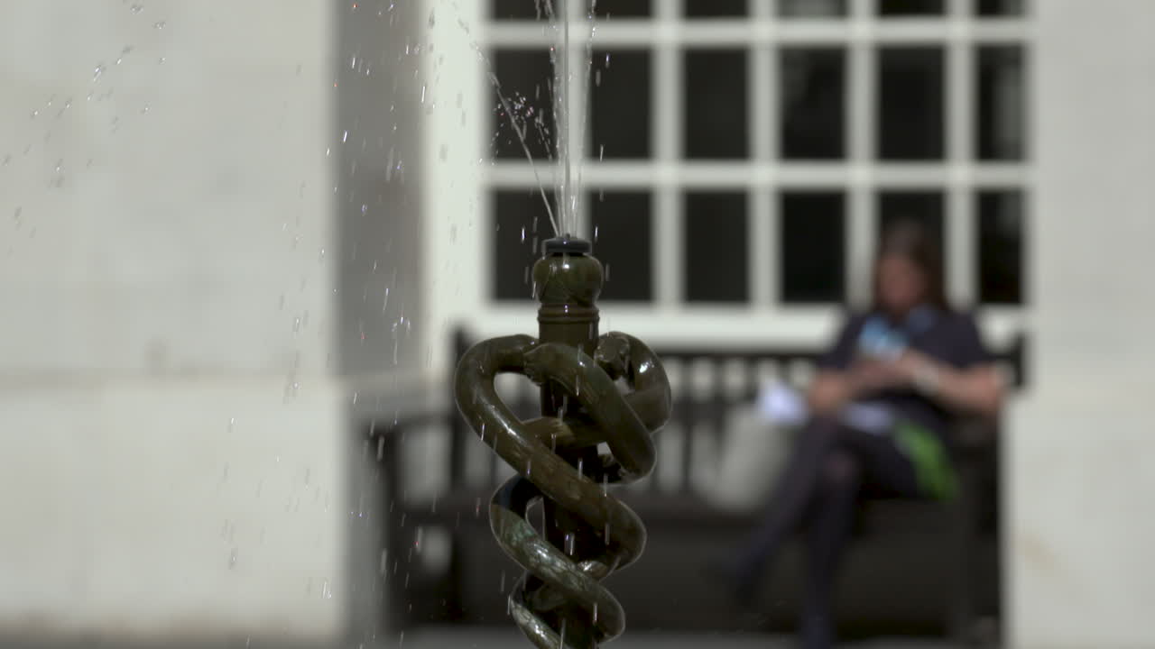 Slow motion water fountain, depicting three entwined snakes, on a Summer's day