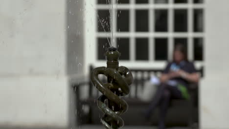 slow motion water fountain, depicting three entwined snakes, on a summer's day