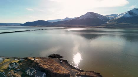 flying out from borgarnes over the fjord water towards a bridge crossing the water towards a spectacular mountain landscape hafjarfjall in the distance