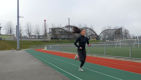 girl jogging on the track, sporty female running tracking shot slomo