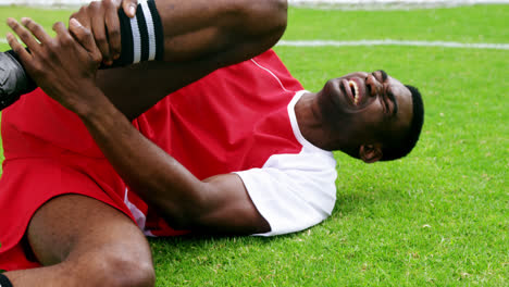 injured football player lying on grass