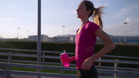woman runner drinking water during sunset workout.