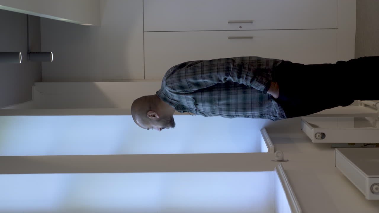 un video vertical de un hombre indio asiático tomando un descanso casual mientras mira por la ventana de una oficina intrigado por las actividades que ve que suceden afuera