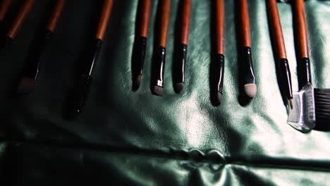 juego de pinceles de maquillaje de madera y metal marrón sobre fondo de cubierta verde brillante con movimiento deslizante