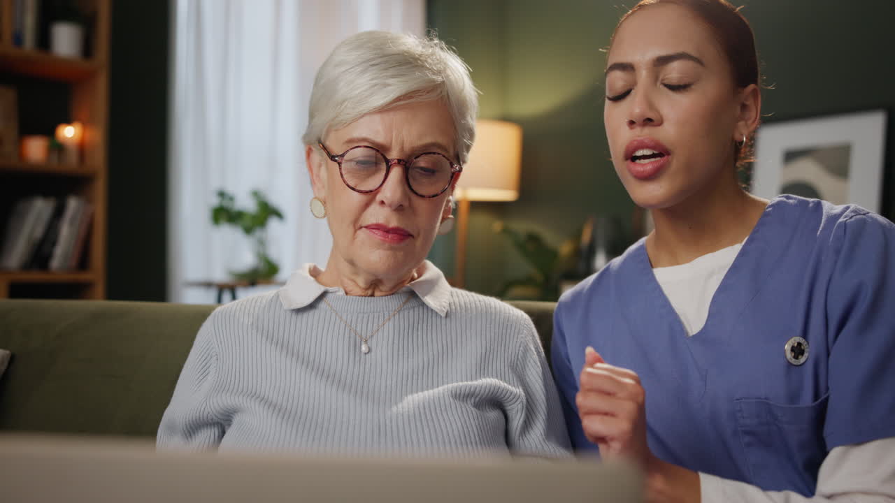 Elderly woman and nurse using laptop