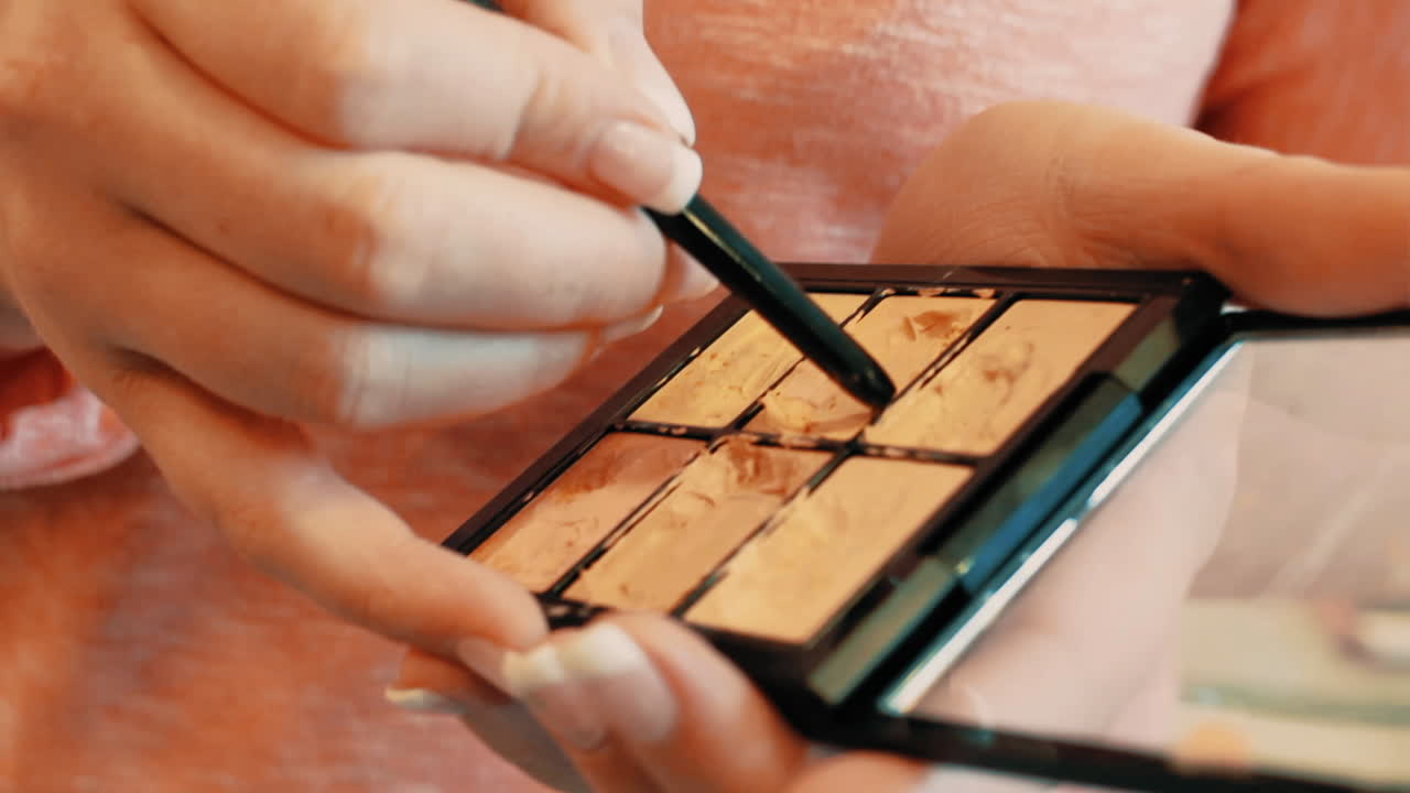 Female artist sorting out make up. Close shot of a professional Makeup Artist applying make up to her arm with the other end of a brush.