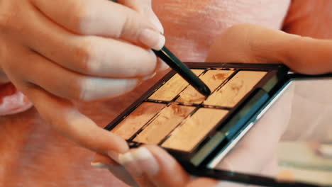 female artist sorting out make up. close shot of a professional makeup artist applying make up to her arm with the other end of a brush.