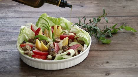 Pouring-olive-oil-into-a-glass-bowl-of-delicious-fresh-salad