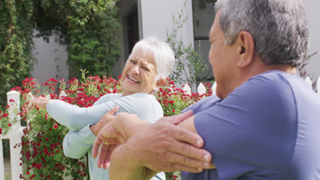 Happy-senior-diverse-couple-practicing-yoga-in-garden