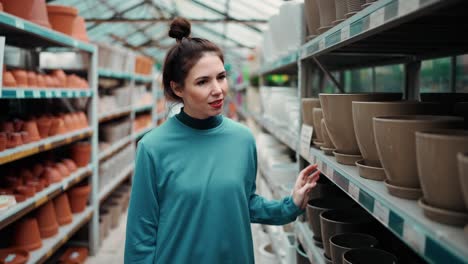 retrato de una mujer joven eligiendo macetas para plantas de interior en el mercado de jardinería