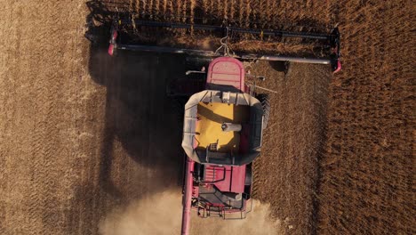 Aerial-rise-up-of-combine-harvesting-soybeans-in-United-States,-Michigan