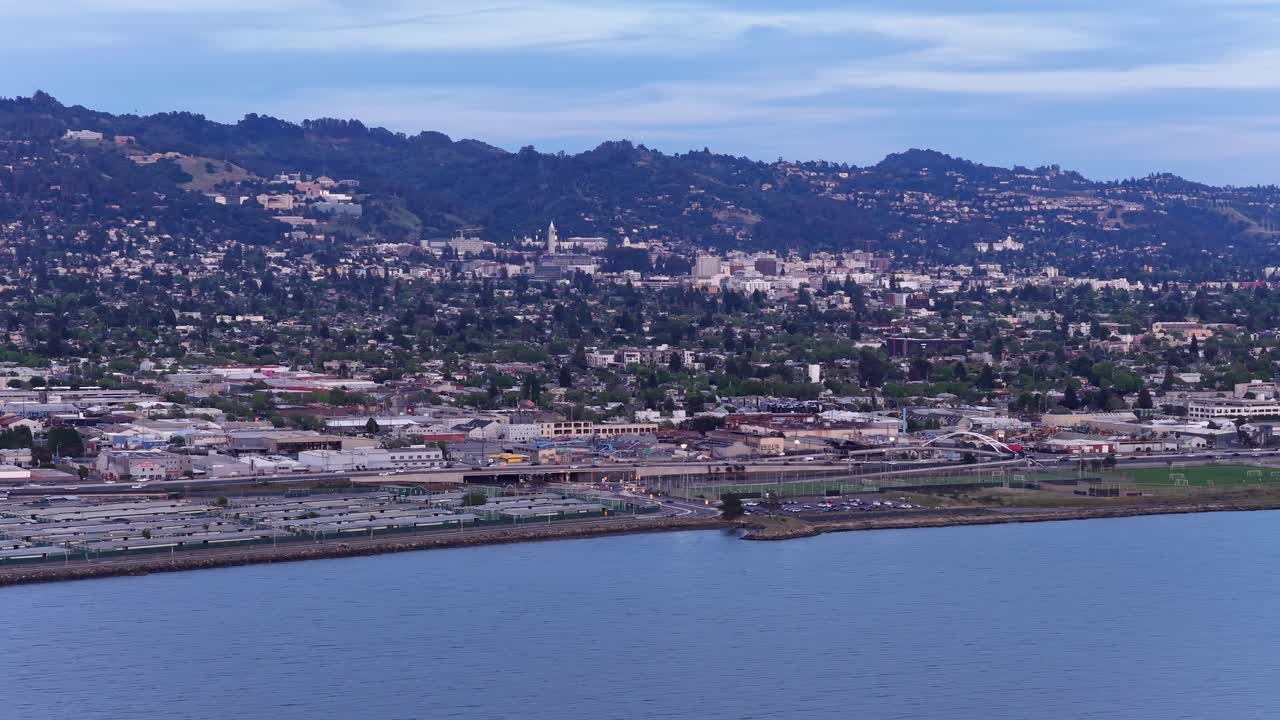 Vista aerea in movimento della città di Albany e delle colline di Berkeley in California, che mostra la costa e il paesaggio urbano con la baia di San Francisco mentre il sole tramonta sulla baia orientale