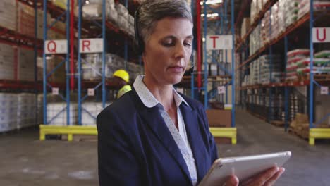 Female-warehouse-manager-talking-with-headset-in-loading-bay-4k