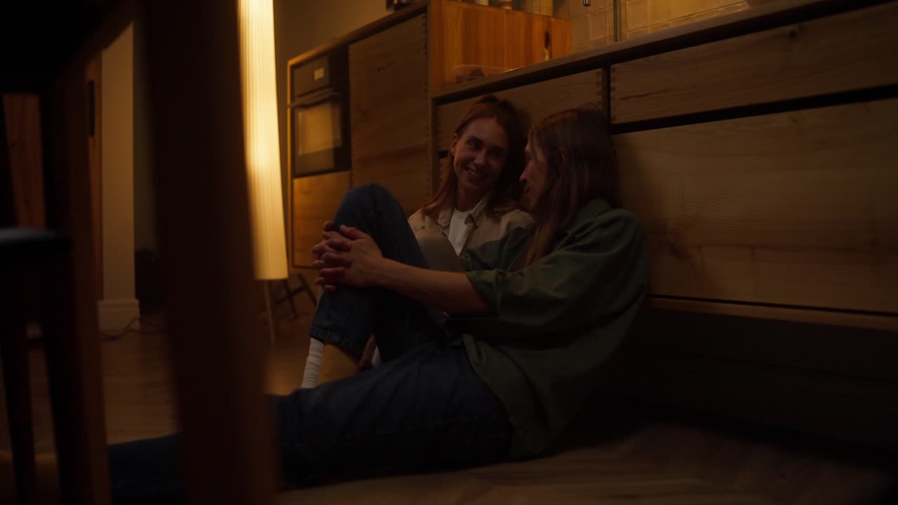 две женщины сидят на полу на кухне