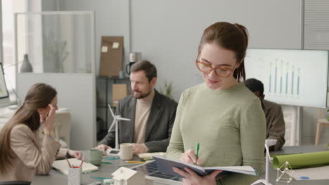 businesswoman writting something on notebook and looking at camera