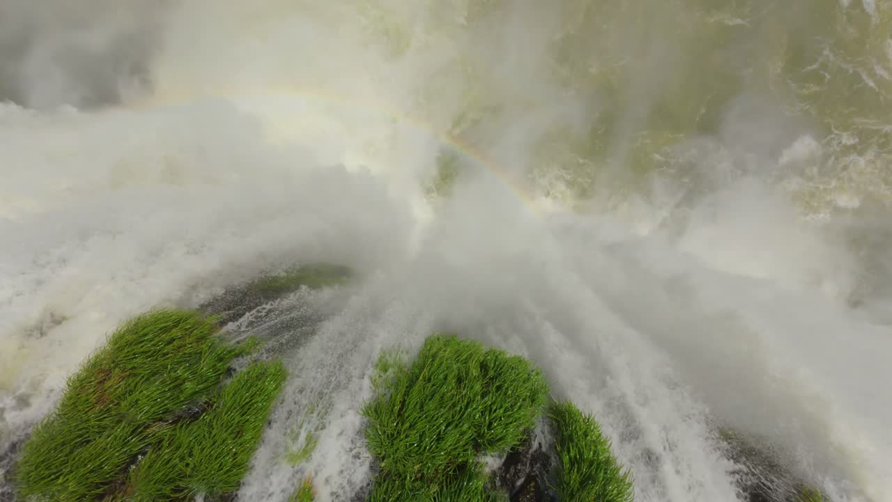 Drone com câmera de cima sobre as Cataratas do Iguaçu, Garganta del Diablo, com arco-íris e árvores verdes