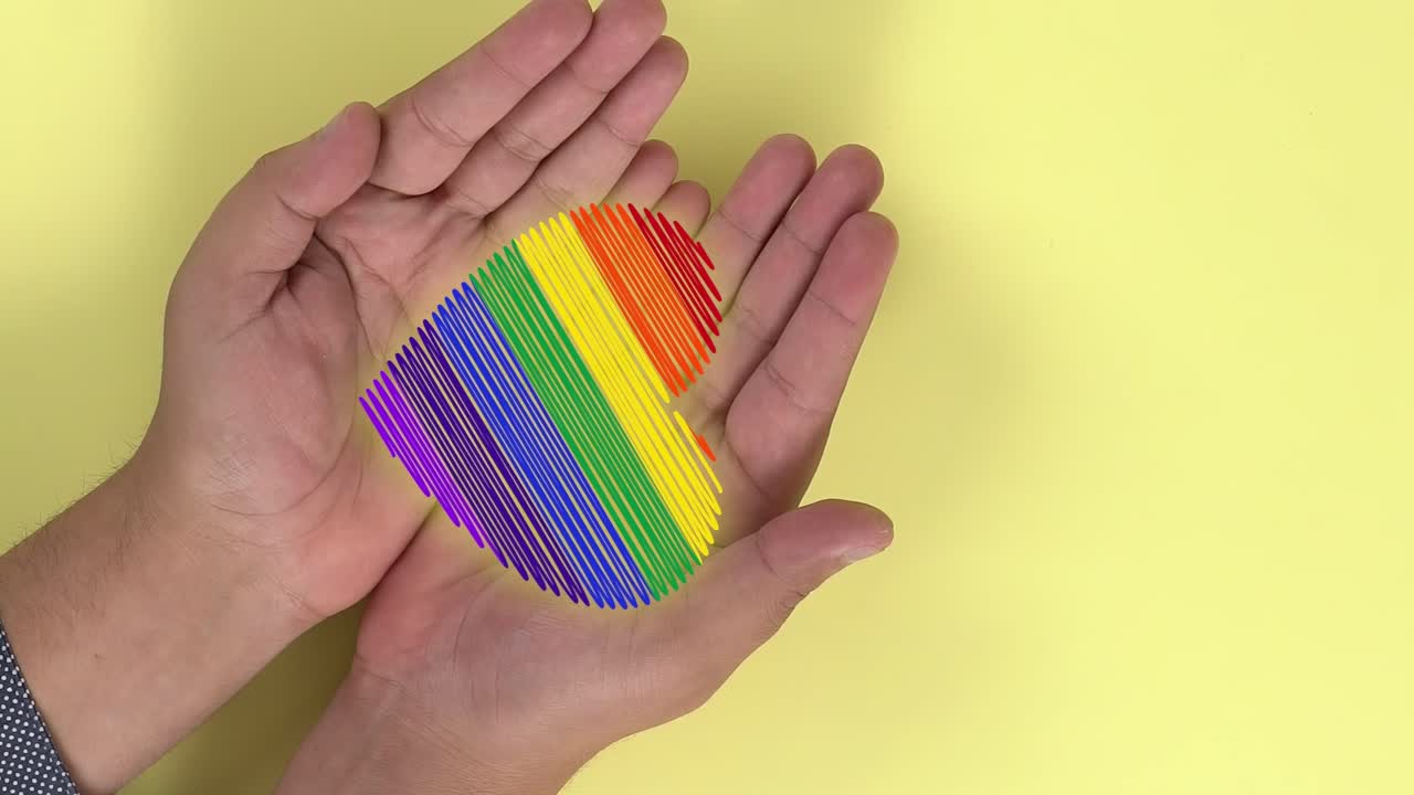 manos de una persona abriéndose y animación de un corazón con colores lgtbi que aparecen en ellas