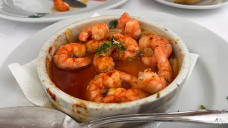 comer gambas españolas tradicionales pil pil con pan en un restaurante en marbella españa, delicioso plato de camarones picantes con ajo, tiro de 4k