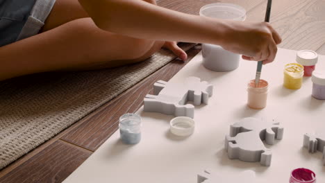 close up view of girl's hands painting animal pieces on the floor