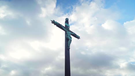 Looking-up-Jesus-cross-statue-on-a-cloudy-and-blue-sky,-powerful-religion-and-faith-symbol