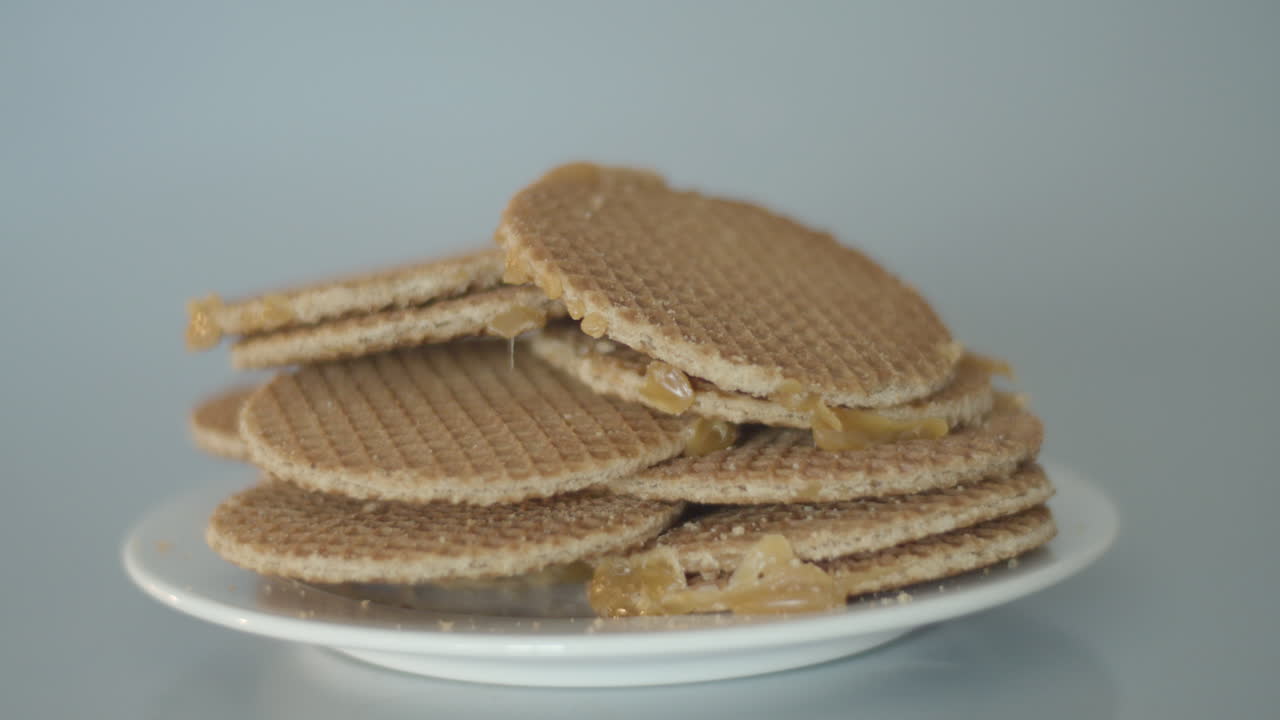 Hand placing a single cookie on a pile of stroopwafels, a typical Dutch treat