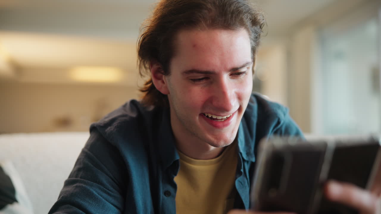 A young man smiling and looking at his phone