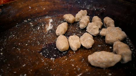 close up of woman's hand placing dough balls in a wooden tray