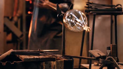 mid section of glassblower shaping a molten glass