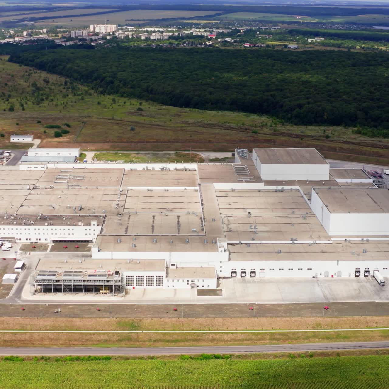 Large industrial territory in nature. Modern plant with car parking from above. Huge manufacturing in the countryside. Aerial view