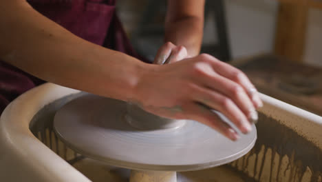 close up view of female potter creating pottery on potters wheel at pottery studio