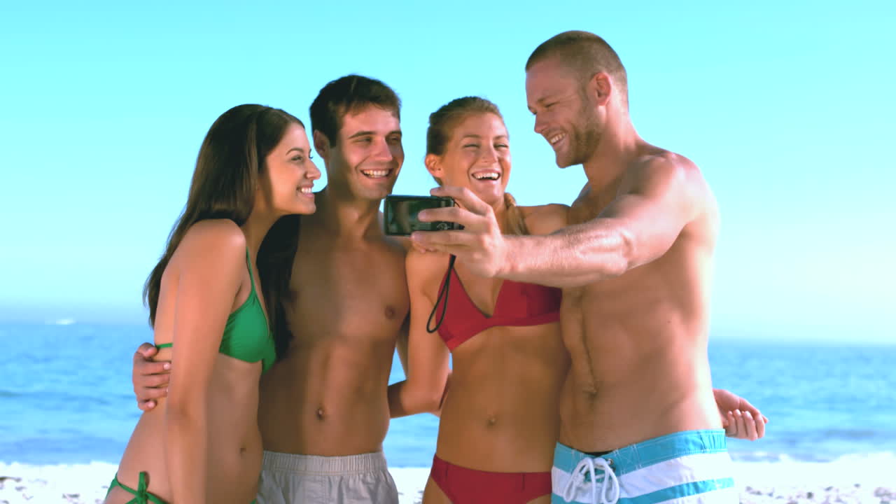 grupo de amigos tomando fotos de sí mismos en la playa