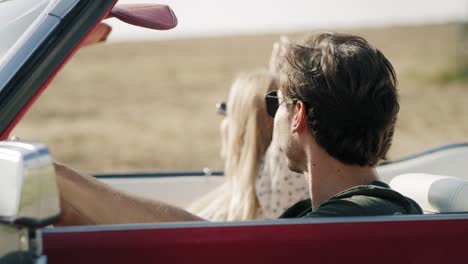 Side-view-of-happy-couple-driving-in-a-cabriolet