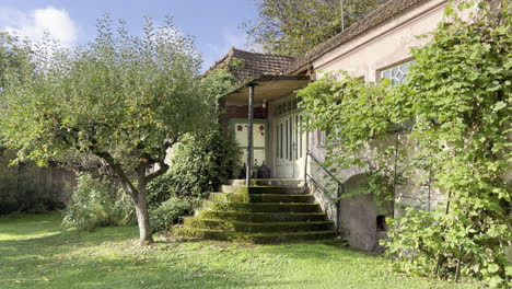 dolly shot of a old romanian house with greenery that envelops the stairs and walls