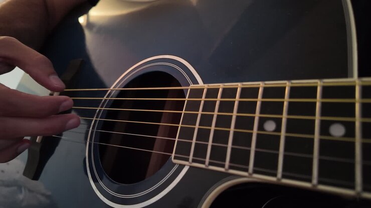 Yandan yakın çekimle gitar tellerini çalan parmaklar.