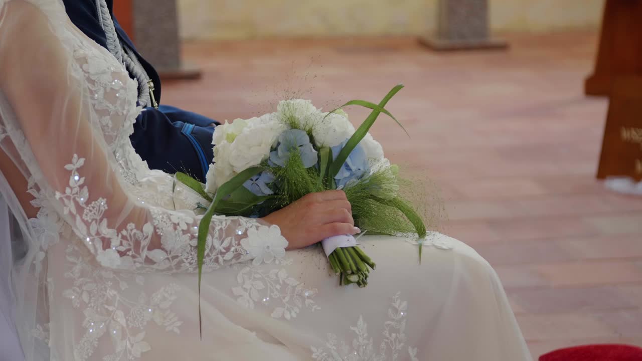 A bride sitting in the church during the wedding ceremony, holding her wedding bouquet