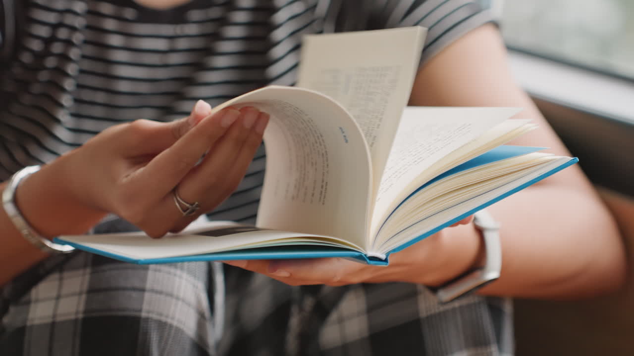Interazione con le pagine di un libro. Vista dettagliata di una mano che gira le pagine. Focalizzazione sulle punte delle dita e sulla rilegatura durante la lettura. Scatto intimo che cattura il processo tattile della lettura in un ambiente d'albergo.