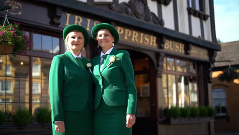 two women in green suits and hats standing outside an irish pub