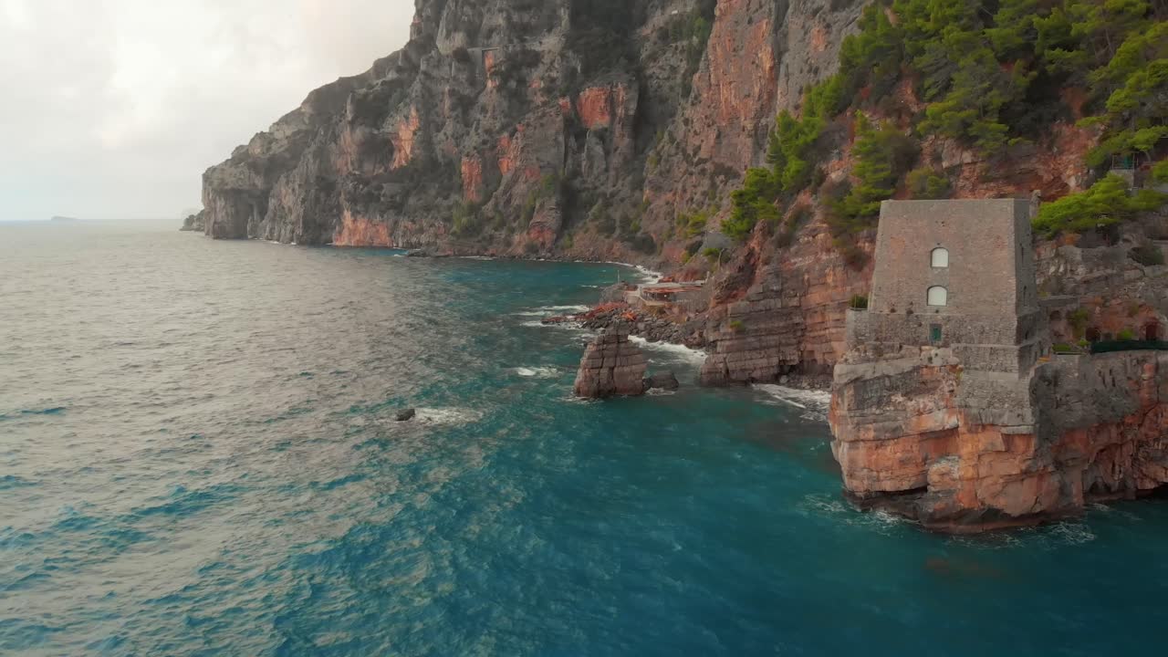 Captivating aerial view of stormy Positano, Italy, showcasing a majestic castle perched on the cliffs, offering a unique Airbnb experience. Filmed by Drone.