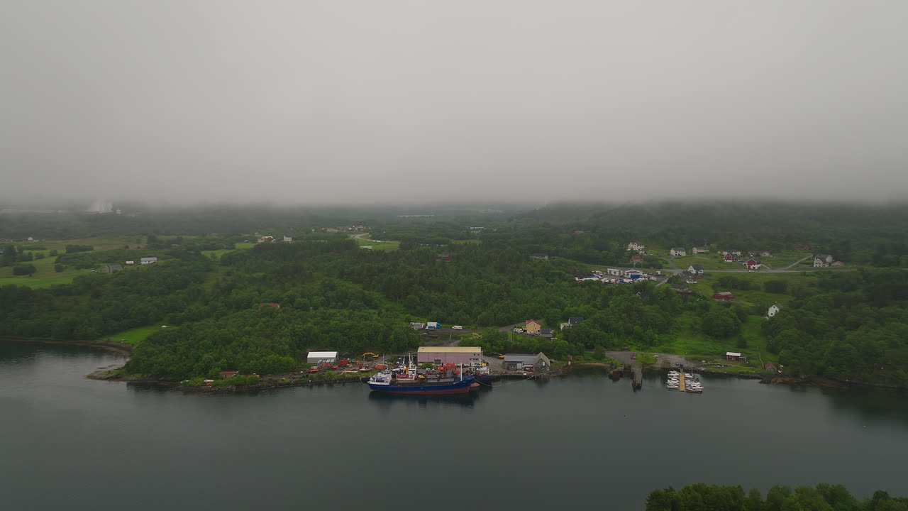 vista aérea del muelle de barcos cerca de la aldea costera en la costa oeste de noruega durante una mañana de niebla