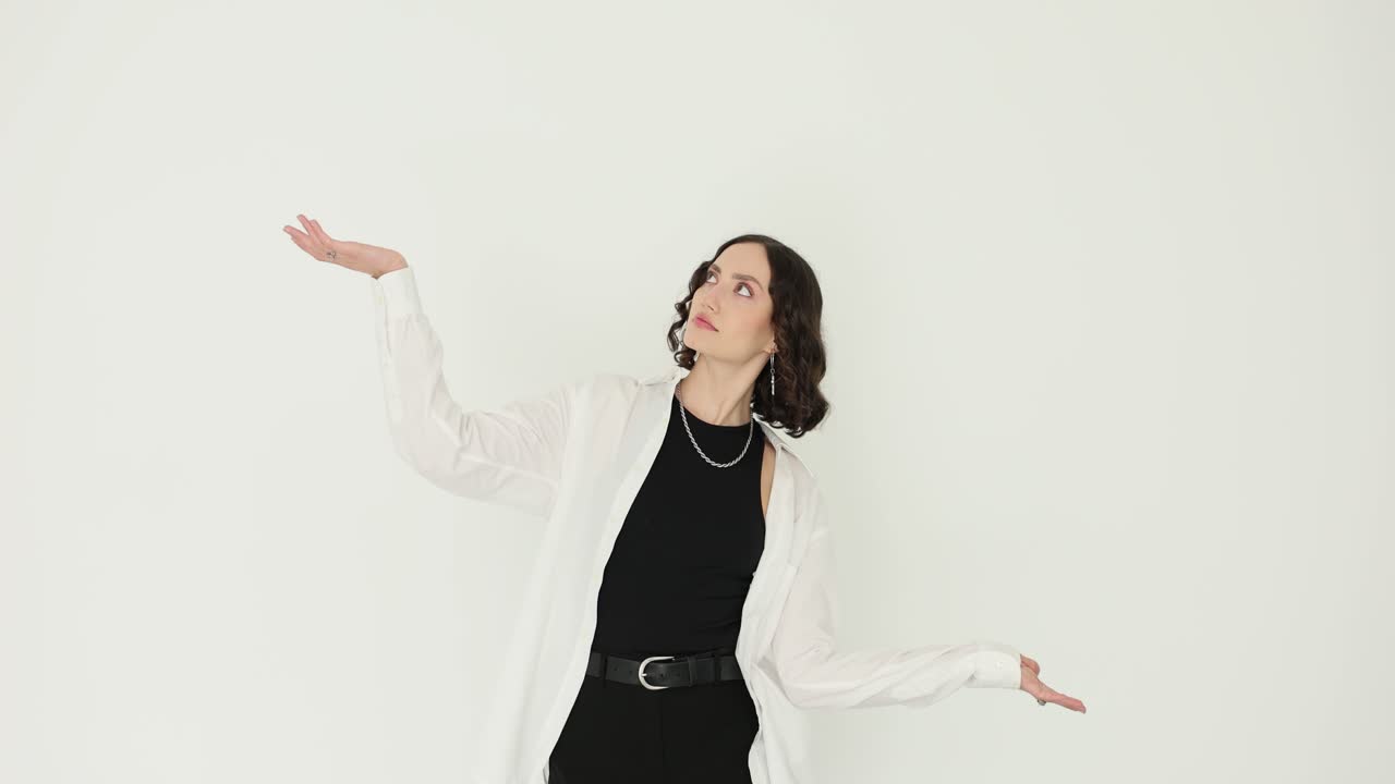 Casual woman spreads arms like balance scale and shrugs