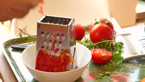 female hands grated tomato in container for paella