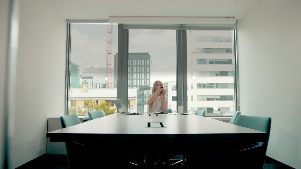 mujer de negocios agitando la mano mientras habla por teléfono. mujer de negocios elegante haciendo una llamada telefónica mientras está sentada en la mesa en la sala de conferencias y agitando la manos para saludar a su colega