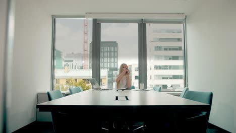 mujer de negocios agitando la mano mientras habla por teléfono. mujer de negocios elegante haciendo una llamada telefónica mientras está sentada en la mesa en la sala de conferencias y agitando la manos para saludar a su colega