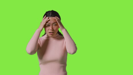 Studio-Portrait-Of-Frustrated-Angry-Woman-Shouting-At-Camera-Standing-Against-Green-Screen